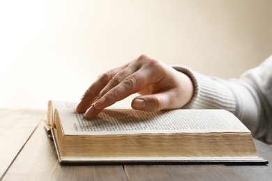 Woman reading Bible at wooden table, closeup