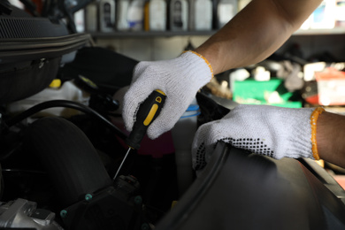 Photo of Professional auto mechanic fixing modern car in service center, closeup