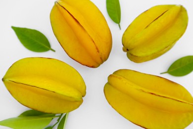 Photo of Delicious ripe carambolas with green leaves on white background