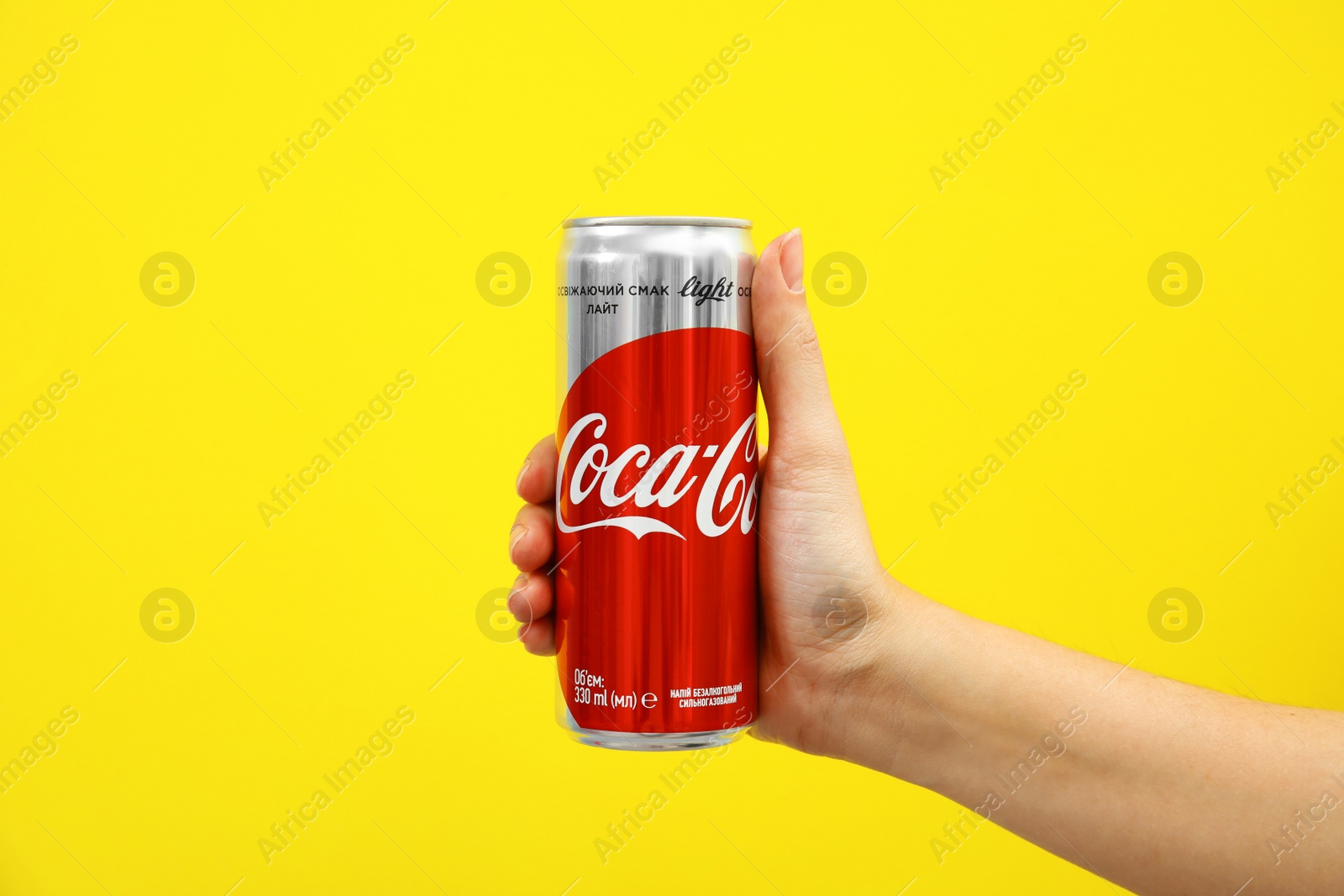 Photo of MYKOLAIV, UKRAINE - NOVEMBER 14, 2018: Woman holding Coca-Cola can on color background