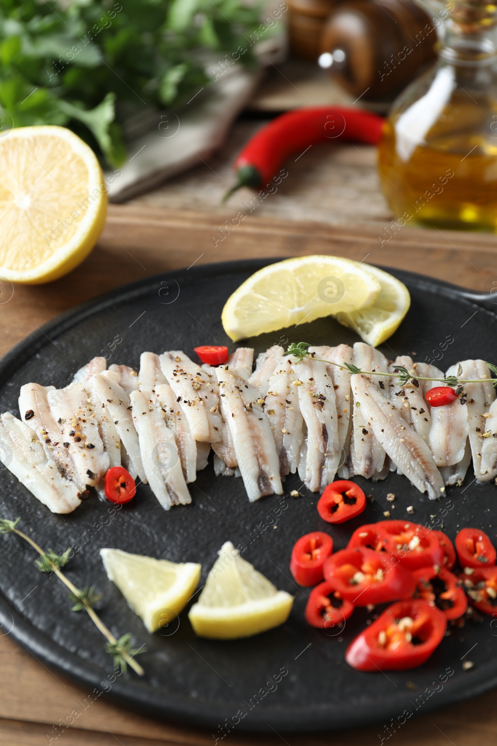 Photo of Tasty anchovies with spices and lemon slices on table