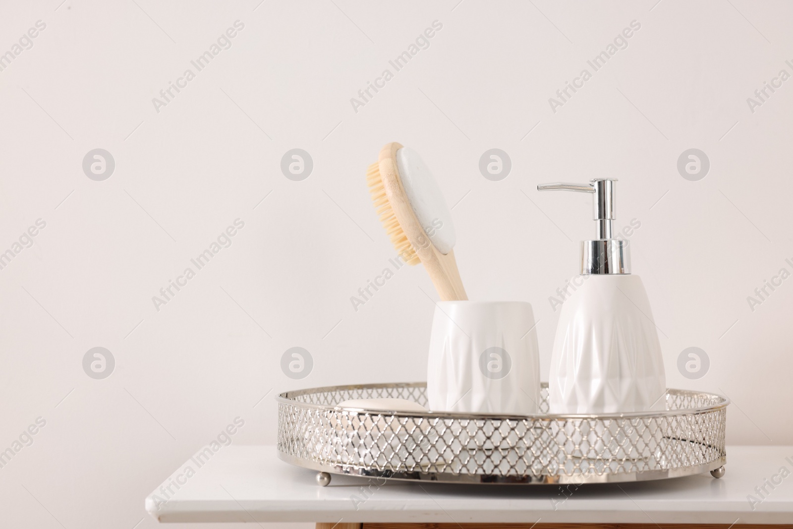 Photo of Different bath accessories and personal care products on table near white wall, space for text