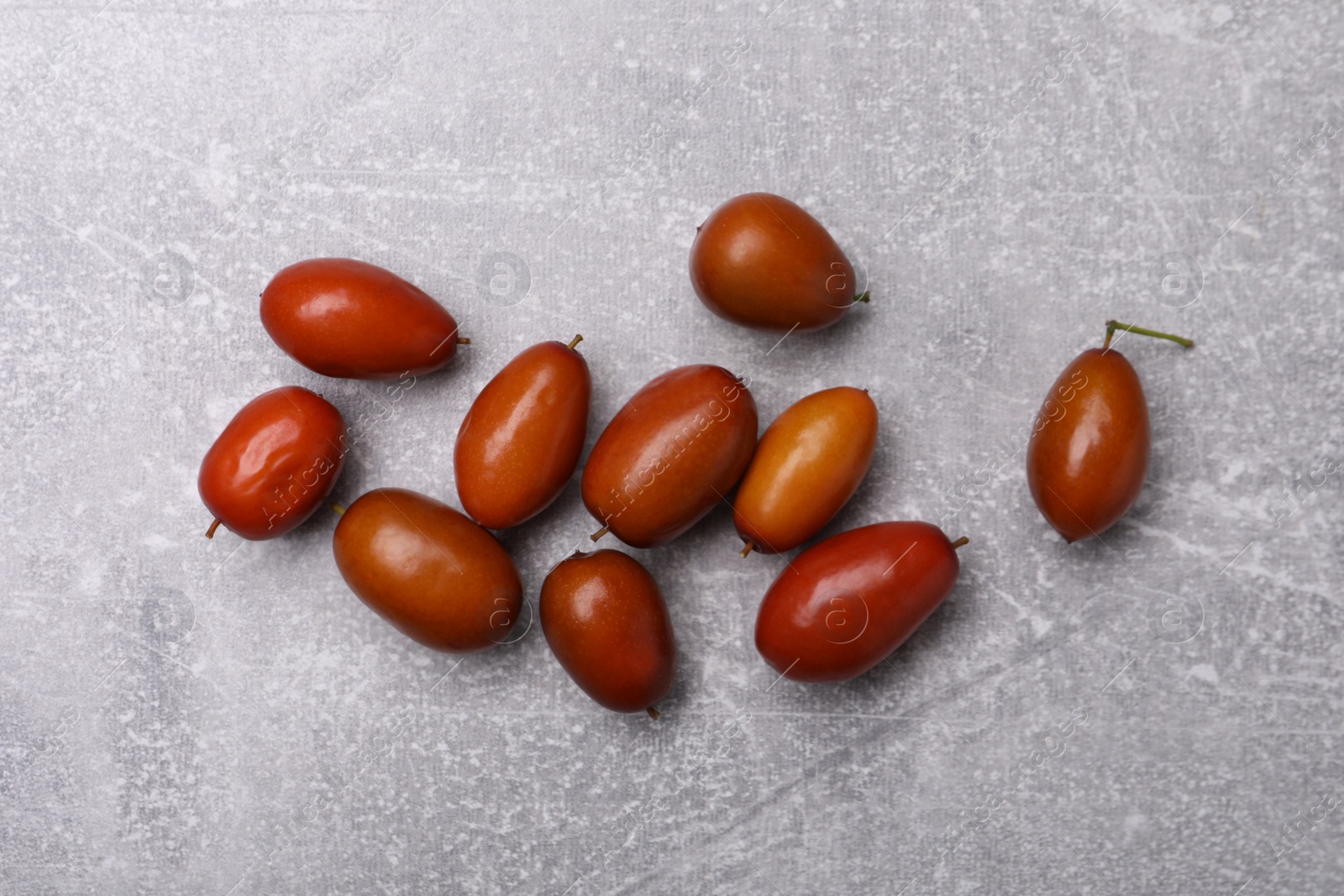 Photo of Fresh Ziziphus jujuba fruits on light table, flat lay