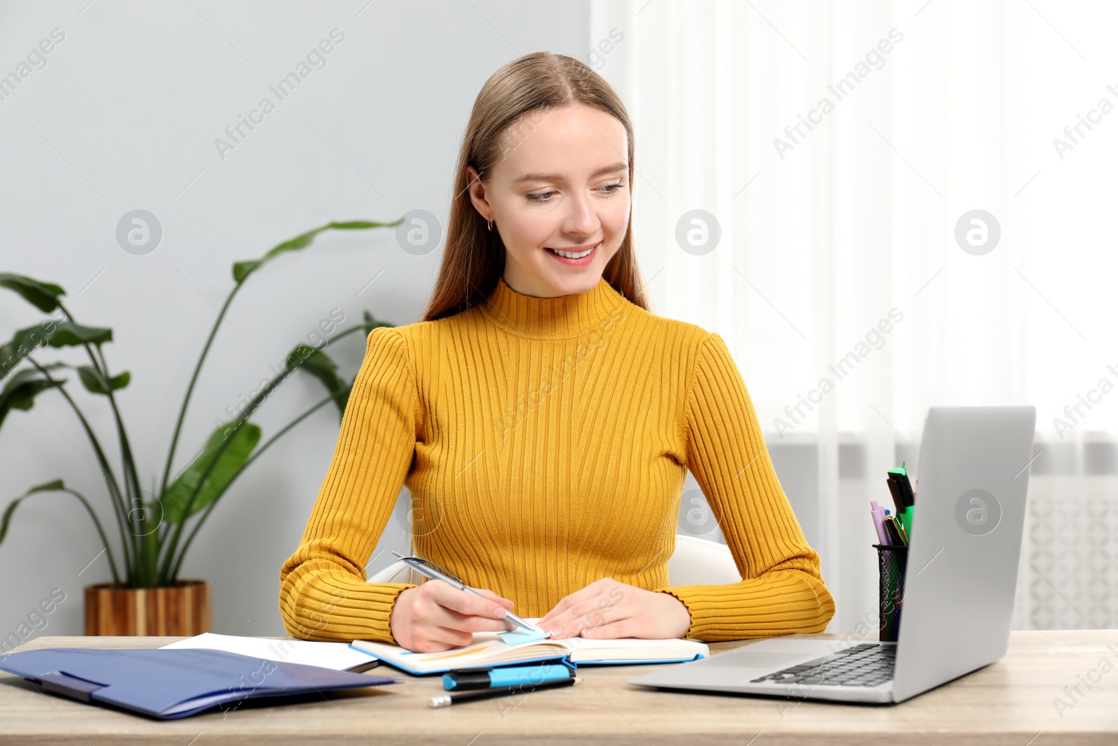 Photo of Woman taking notes at wooden table in office