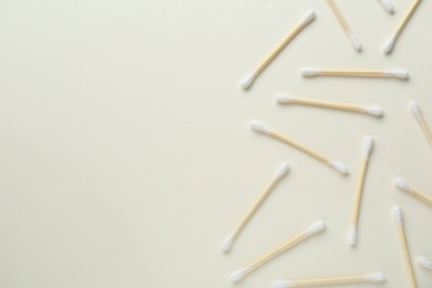 Photo of Many wooden cotton buds on beige background, flat lay. Space for text