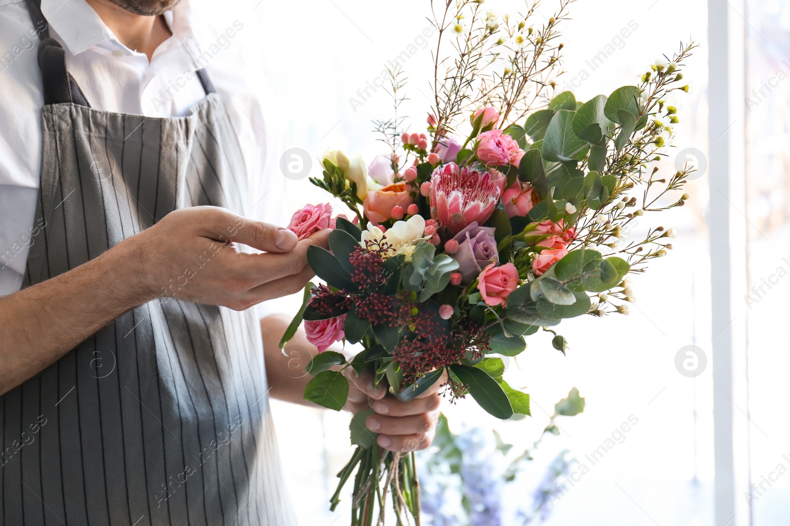 Photo of Male florist creating beautiful bouquet, closeup