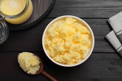Photo of Ghee butter in dishware on wooden table, flat lay