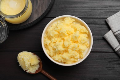 Ghee butter in dishware on wooden table, flat lay