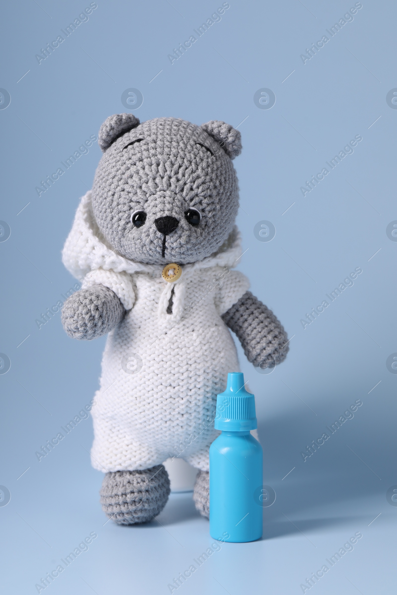 Photo of Toy bear and nasal spray on light blue background