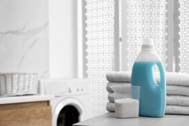 Stack of folded towels and detergents on white table in bathroom, space for text