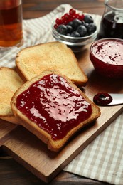 Photo of Delicious toasts with jam served on wooden table, closeup