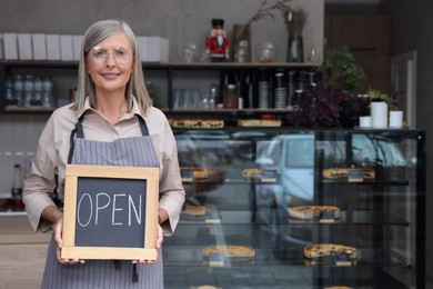 Photo of Happy business owner holding open sign in her cafe, space for text
