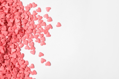 Photo of Pink heart shaped sprinkles on white background, flat lay. Space for text
