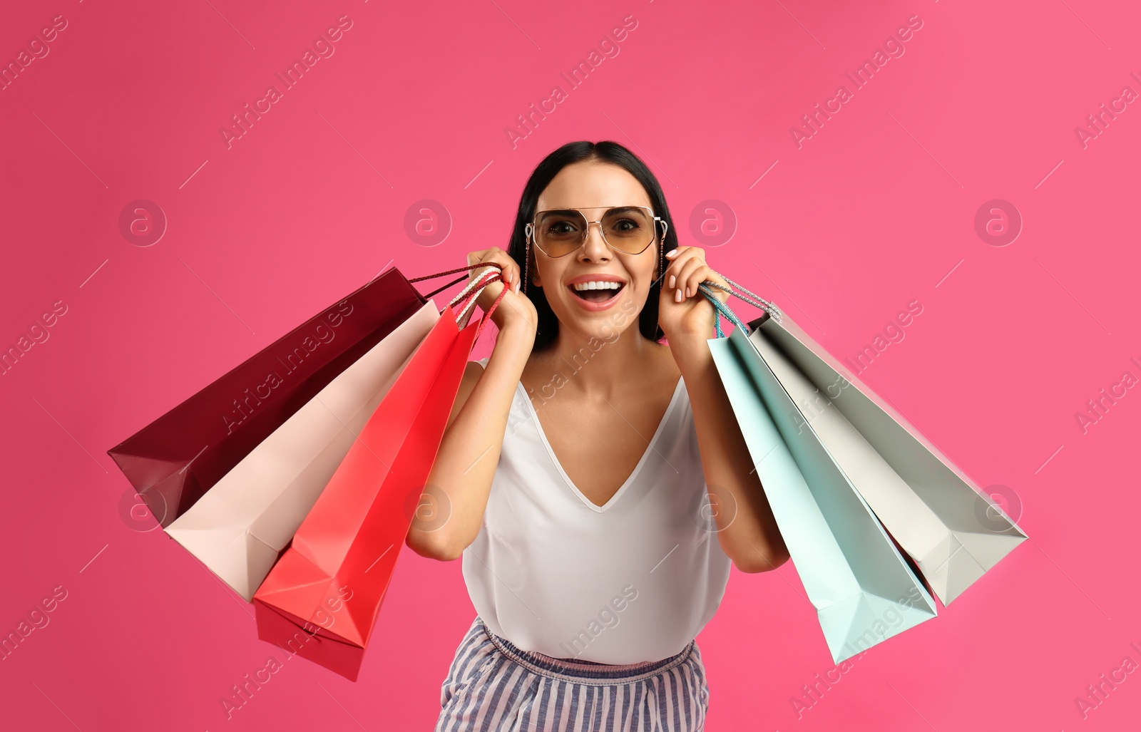 Photo of Beautiful young woman with paper shopping bags on pink background