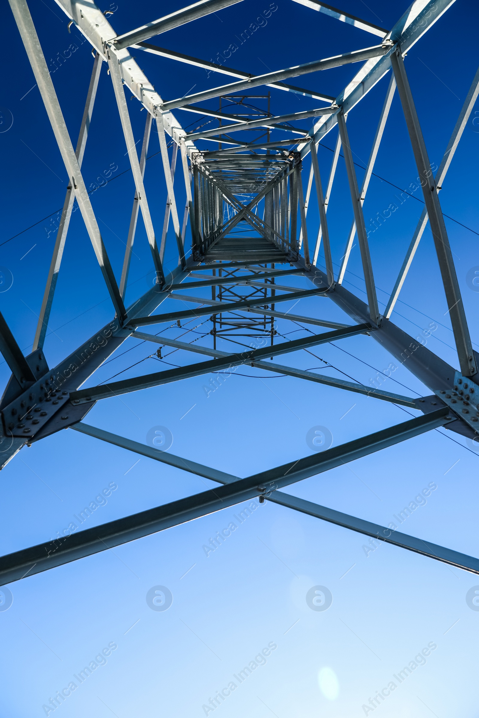 Photo of Modern high voltage tower against blue sky, bottom view