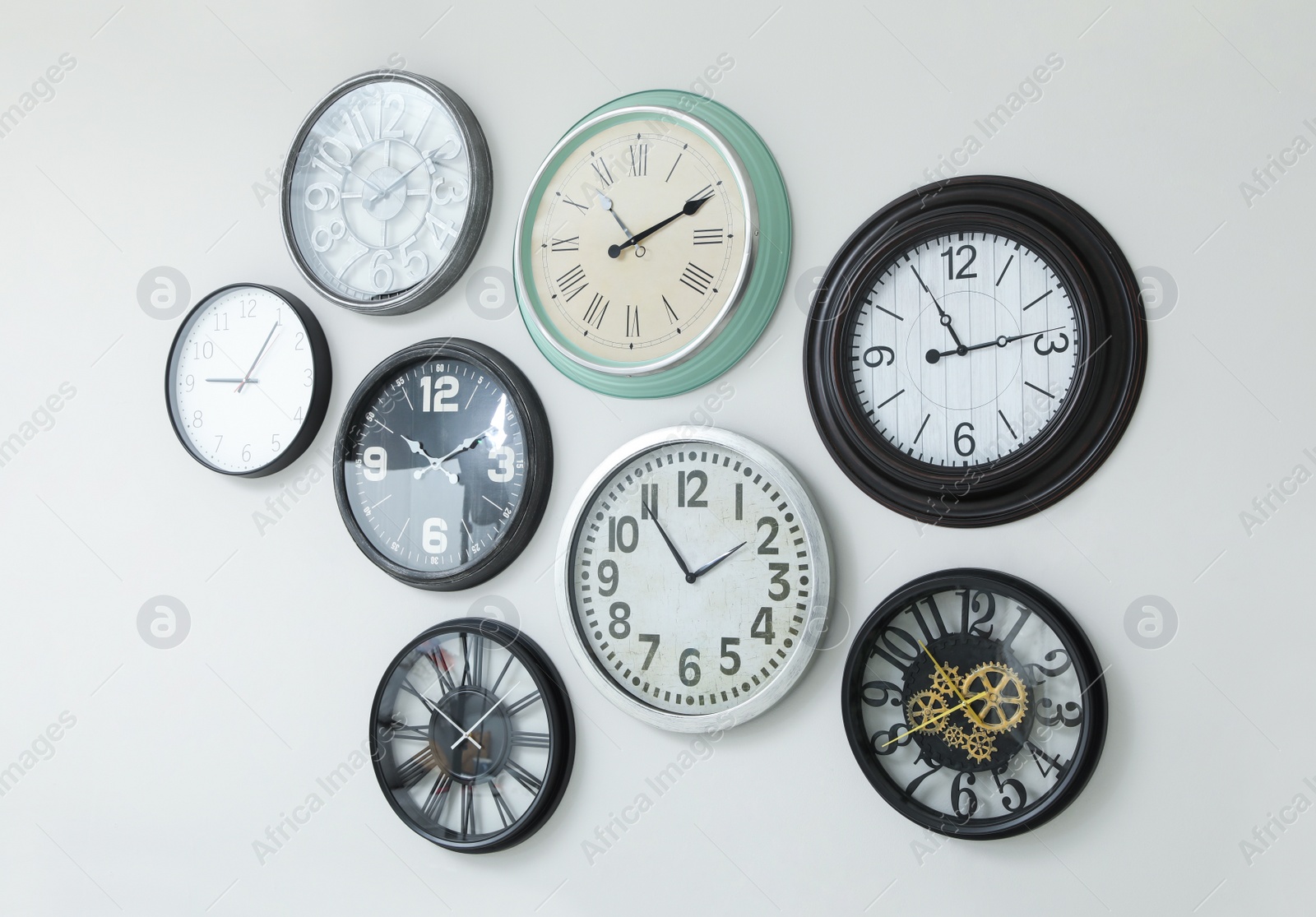 Photo of Many different clocks hanging on white wall.