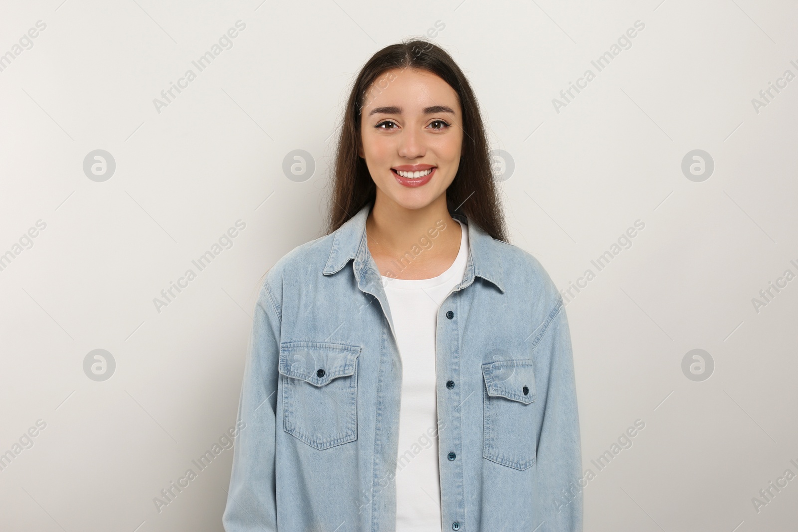 Photo of Portrait of happy young woman in jeans jacket on white background