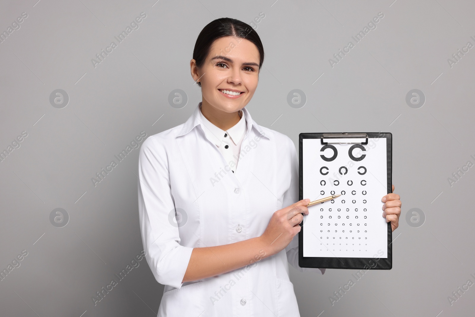 Photo of Ophthalmologist pointing at vision test chart on gray background