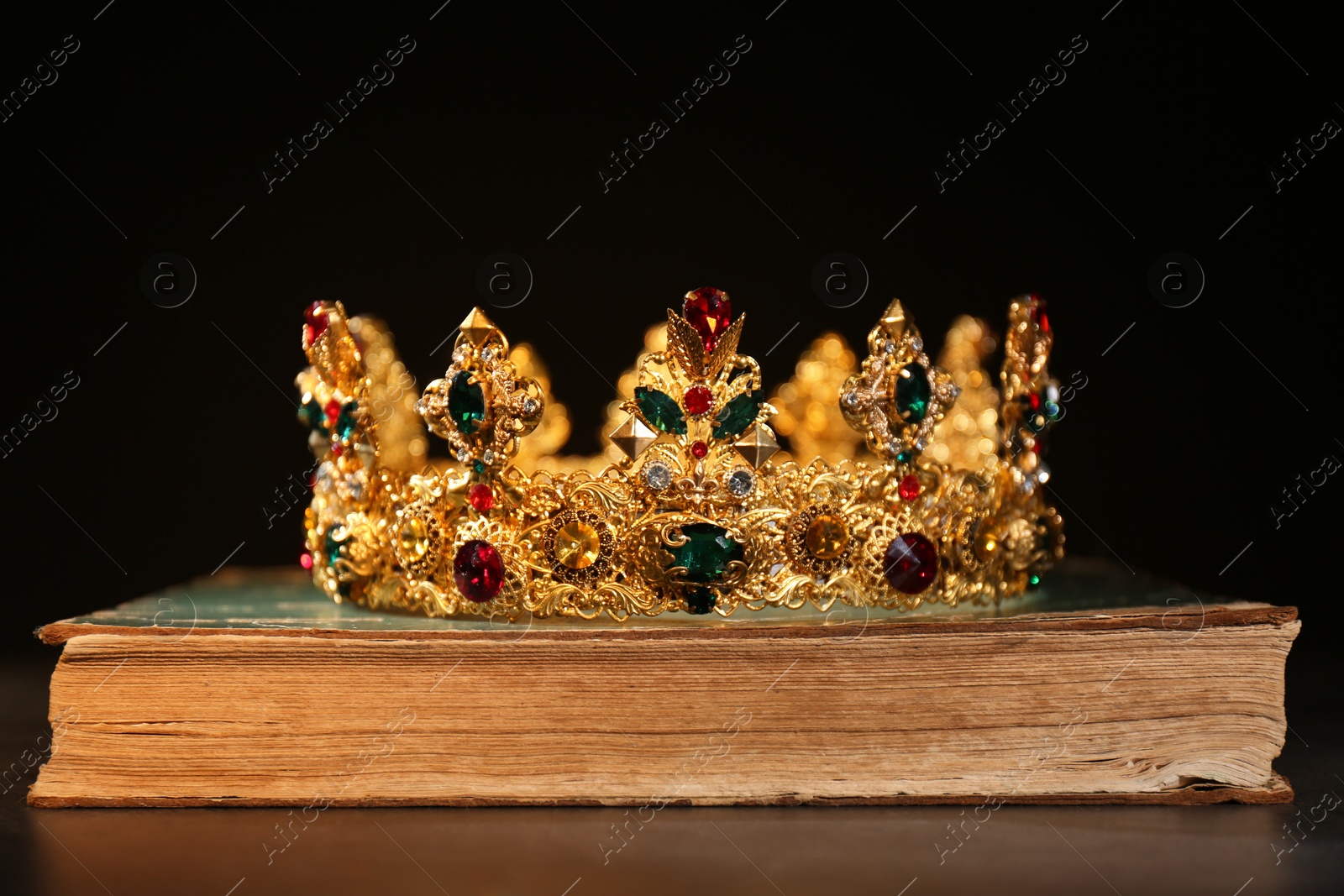 Photo of Beautiful golden crown on old book against black background. Fantasy item