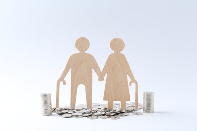 Pension savings. Figure of senior couple and coins on white background