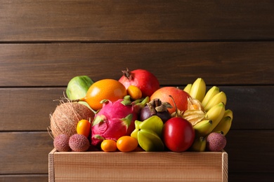 Crate with different exotic fruits on wooden background