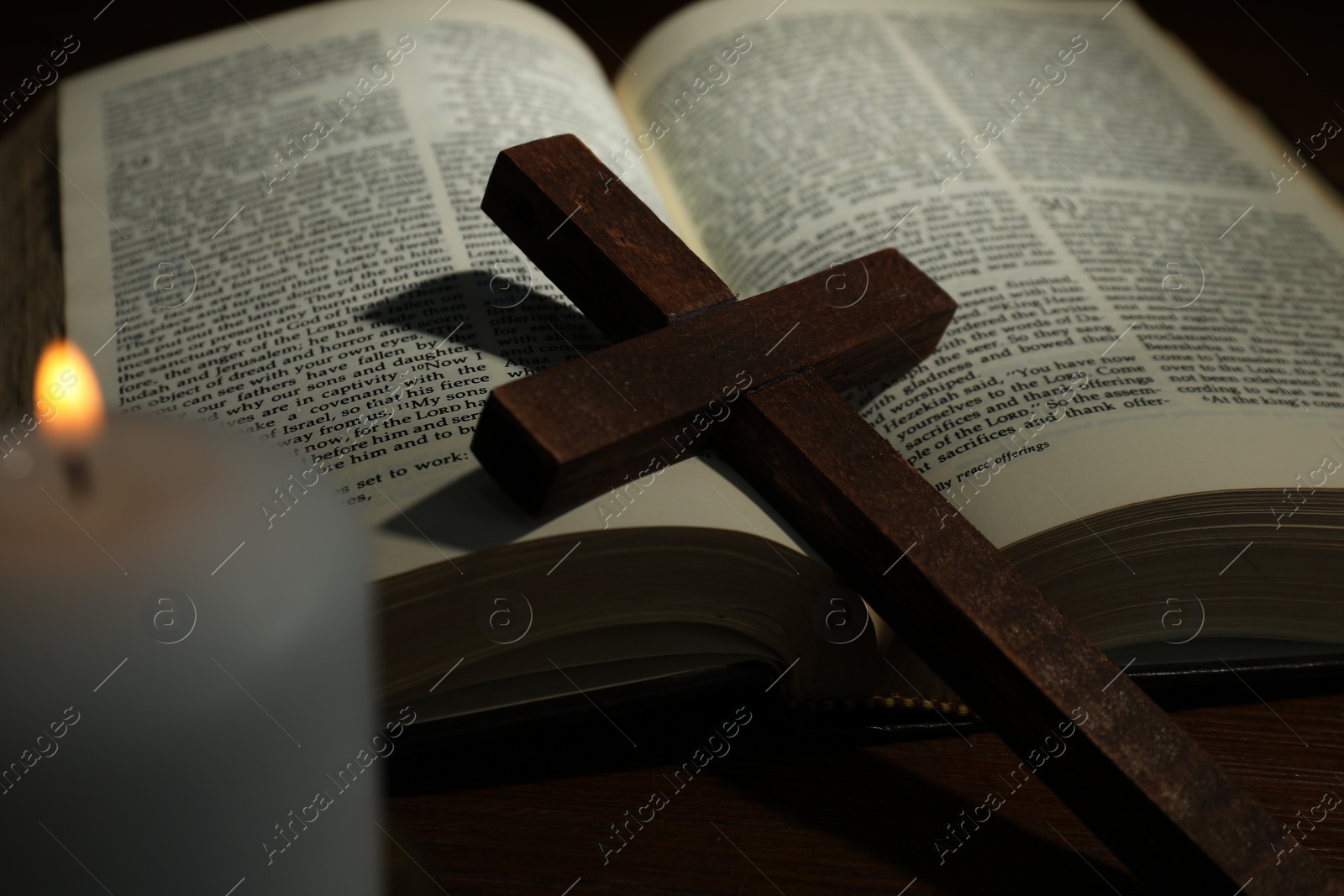 Photo of Cross, Bible and church candle on wooden table