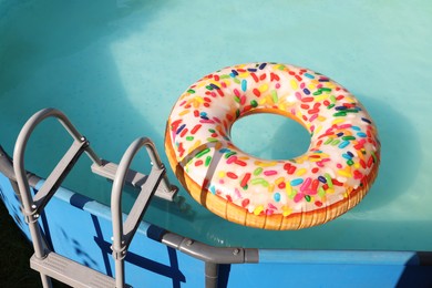 Photo of Inflatable ring floating on water in above ground swimming pool outdoors