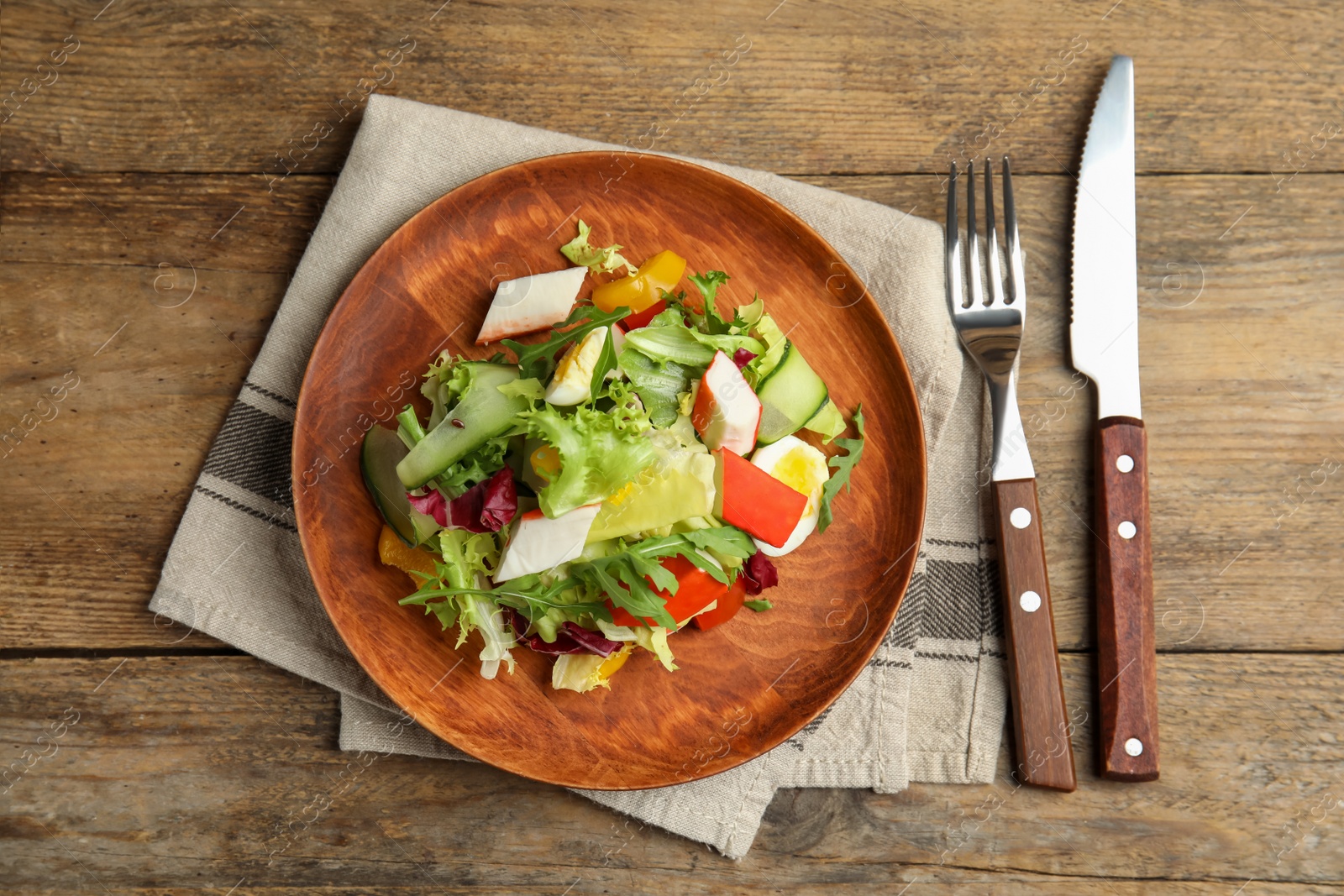 Photo of Delicious salad with crab sticks and lettuce served on wooden table, flat lay