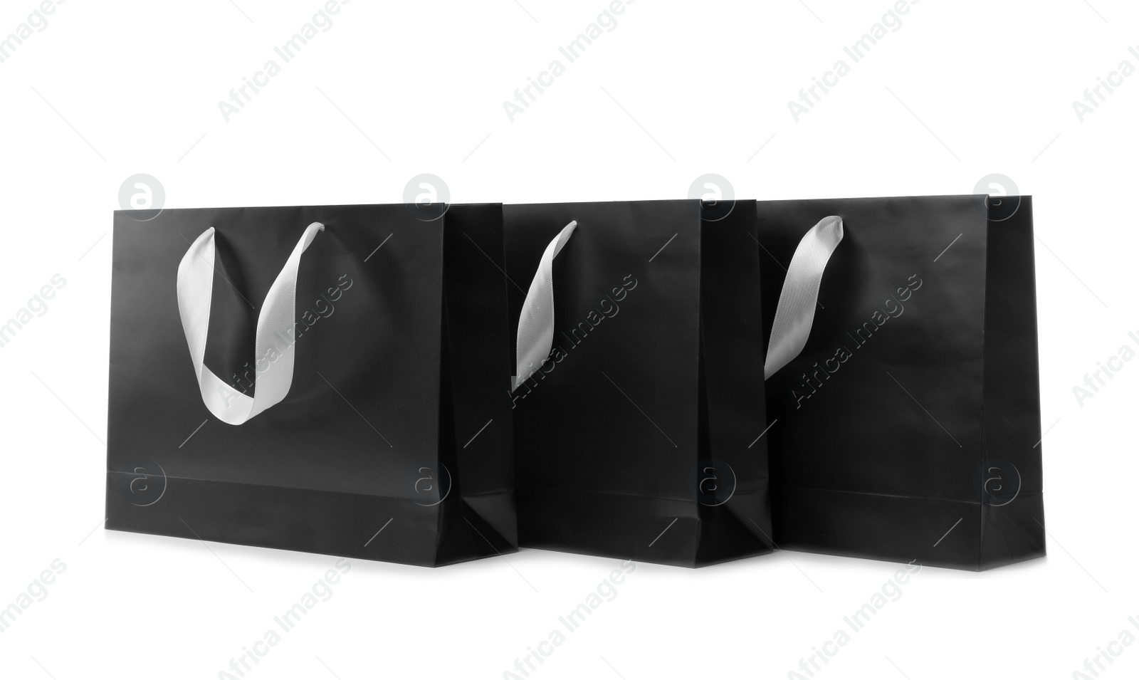 Photo of Paper shopping bags with ribbon handles on white background. Mockup for design