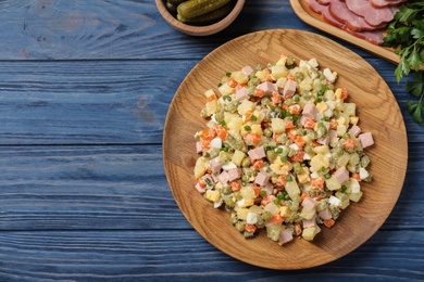 Delicious salad Olivier on blue wooden table, top view. Space for text