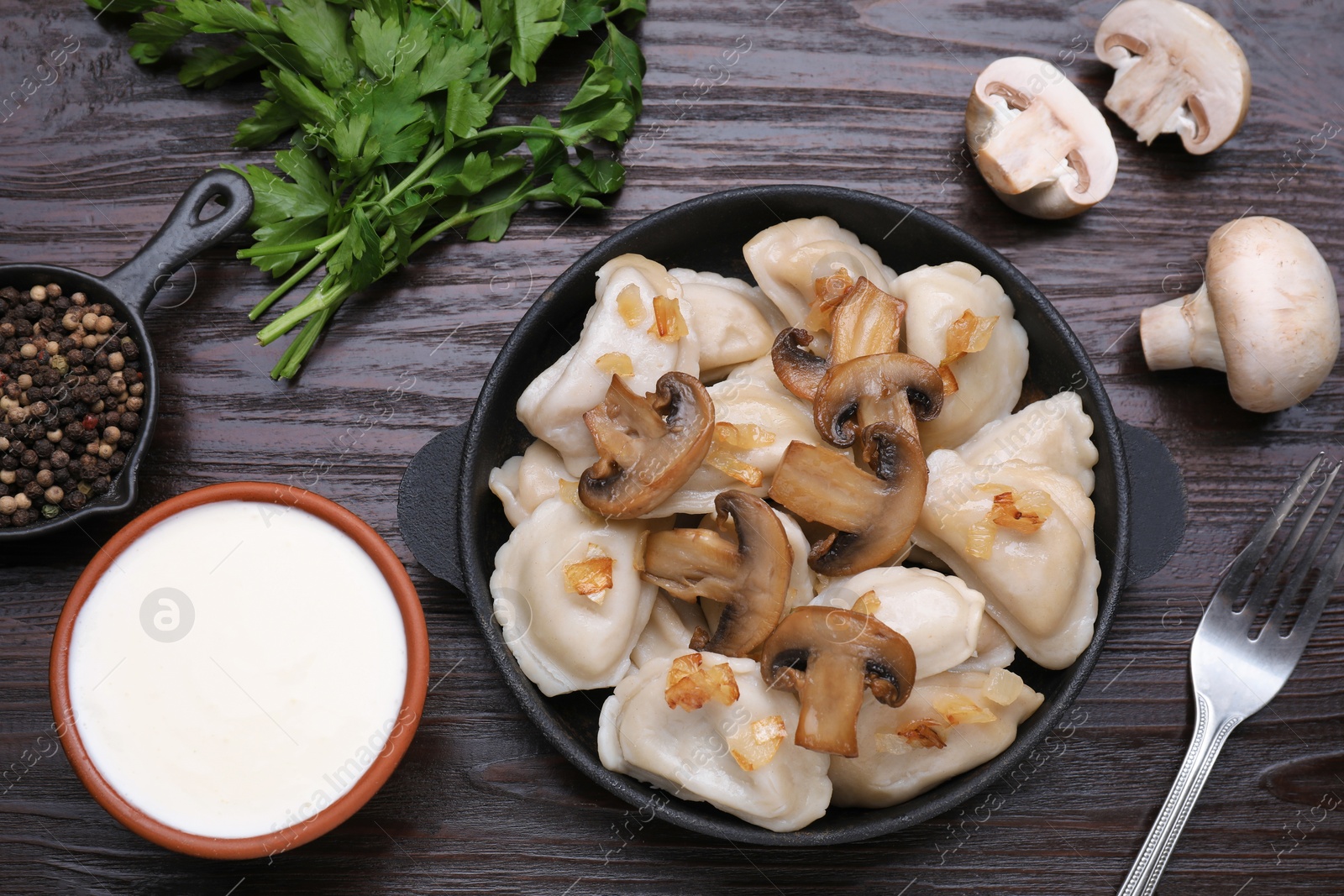 Photo of Delicious dumplings (varenyky) with potatoes, onion and mushrooms served on brown wooden table, flat lay