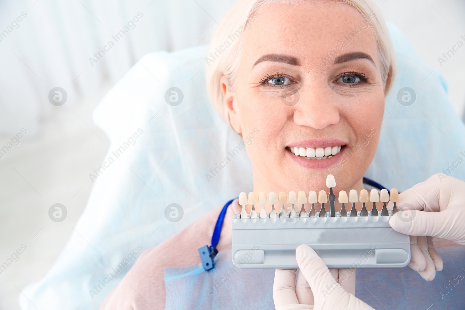 Photo of Dentist selecting patient's teeth color with palette in clinic. Space for text