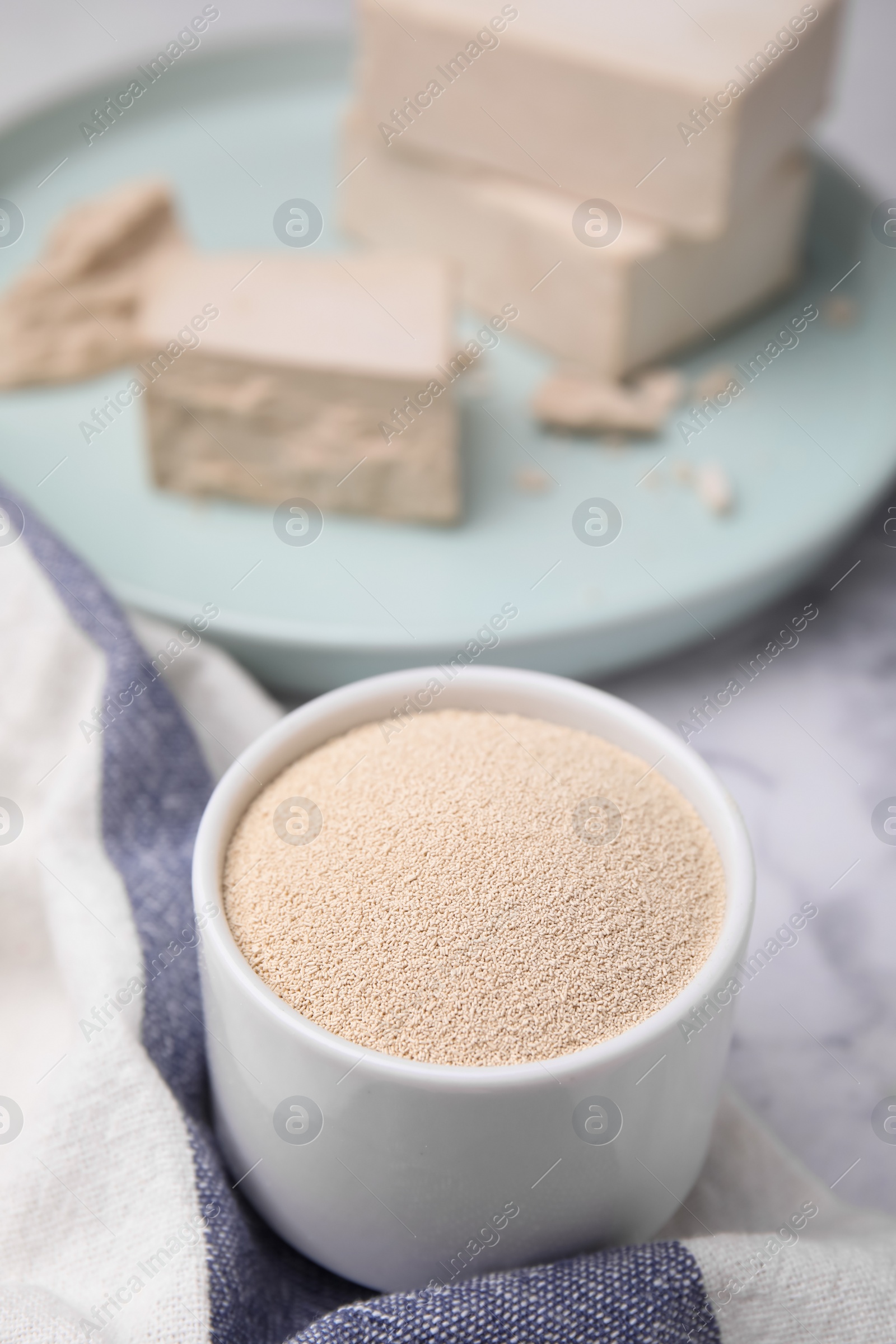 Photo of Granulated yeast in bowl on table, closeup