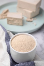 Photo of Granulated yeast in bowl on table, closeup