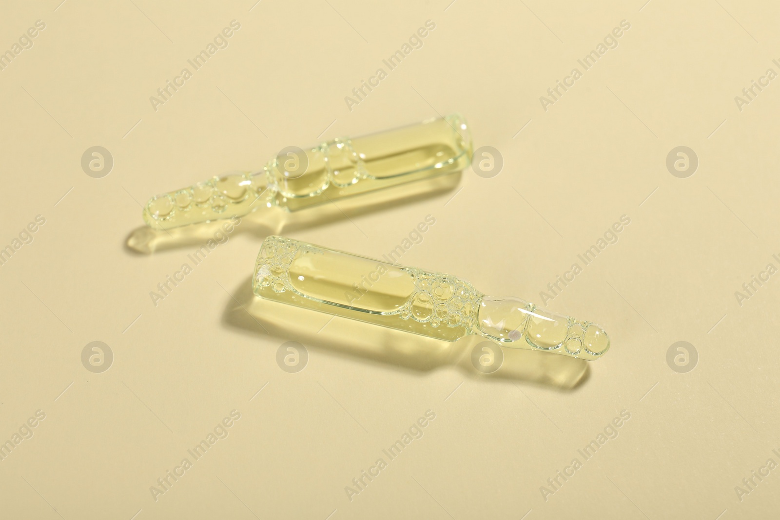 Photo of Glass ampoules with liquid on beige background