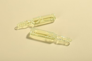 Photo of Glass ampoules with liquid on beige background