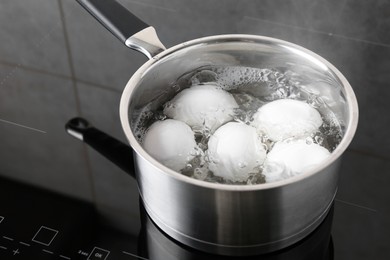 Photo of Chicken eggs boiling in saucepan on electric stove