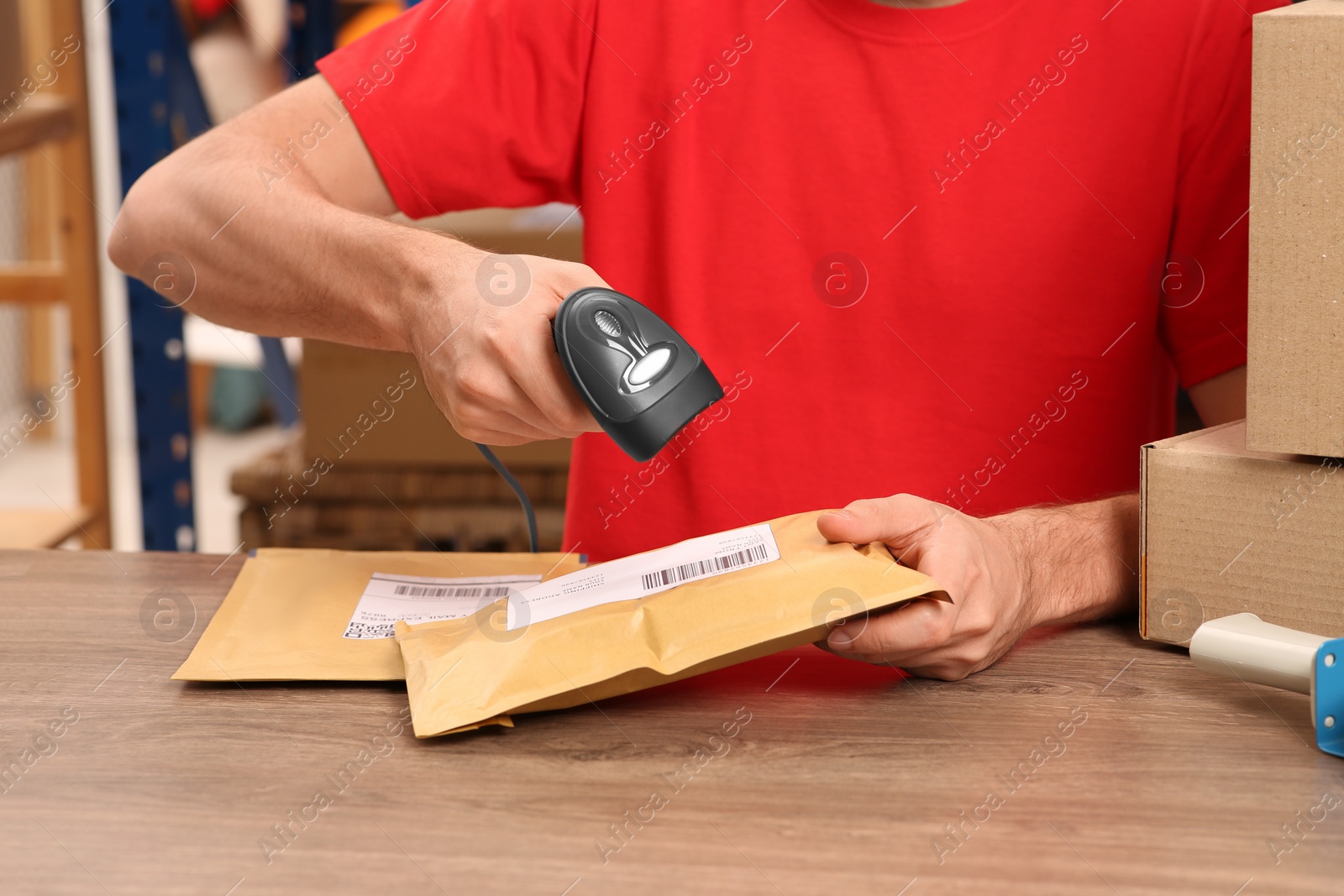 Photo of Post office worker with scanner reading parcel barcode at counter, closeup