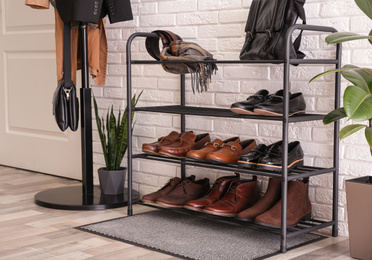 Photo of Shelving rack with stylish shoes and accessories near white brick wall indoors
