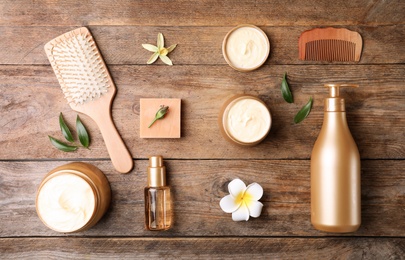 Photo of Flat lay composition with hair cosmetic products on wooden table