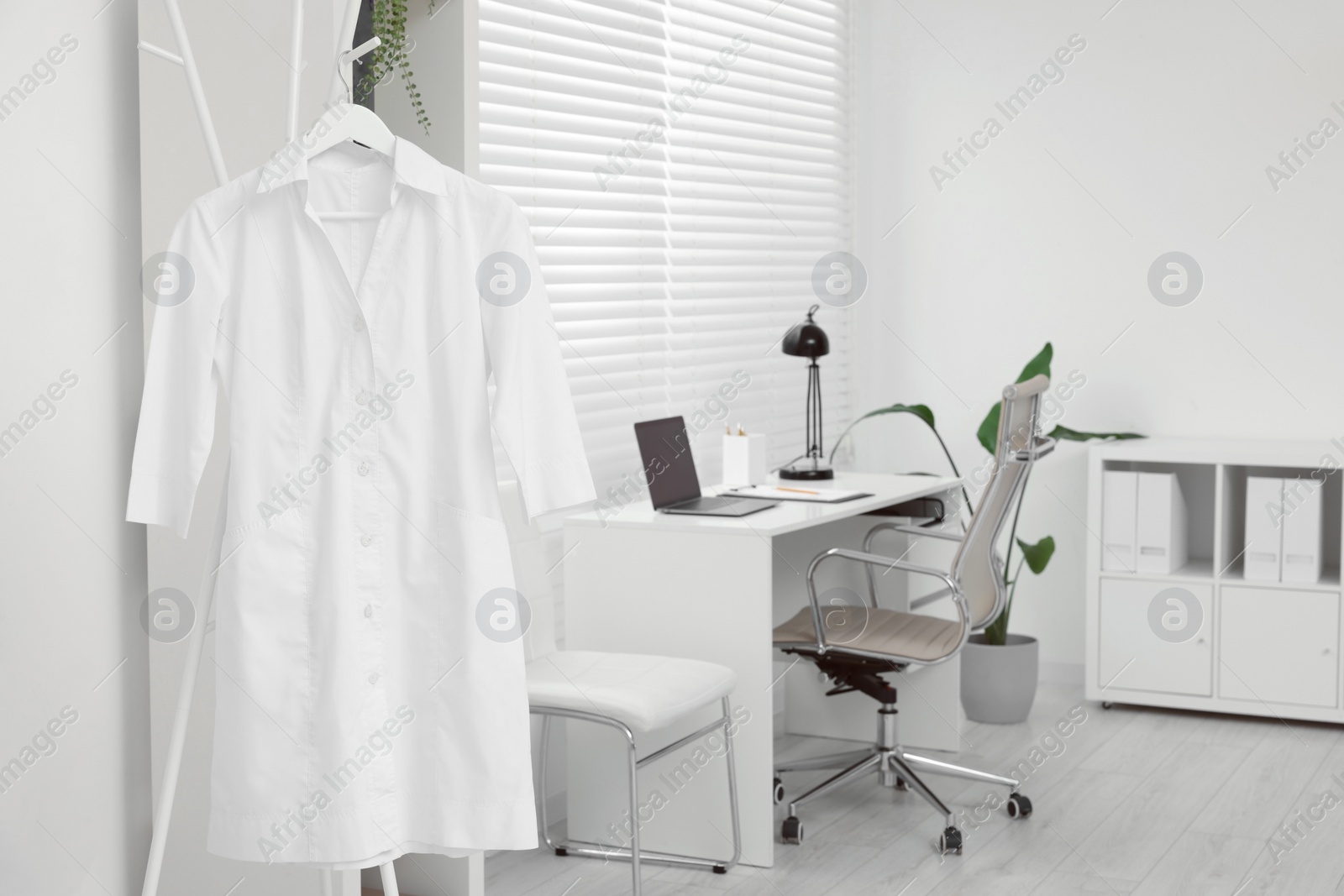 Photo of Doctor's gown on hanger near workplace in clinic