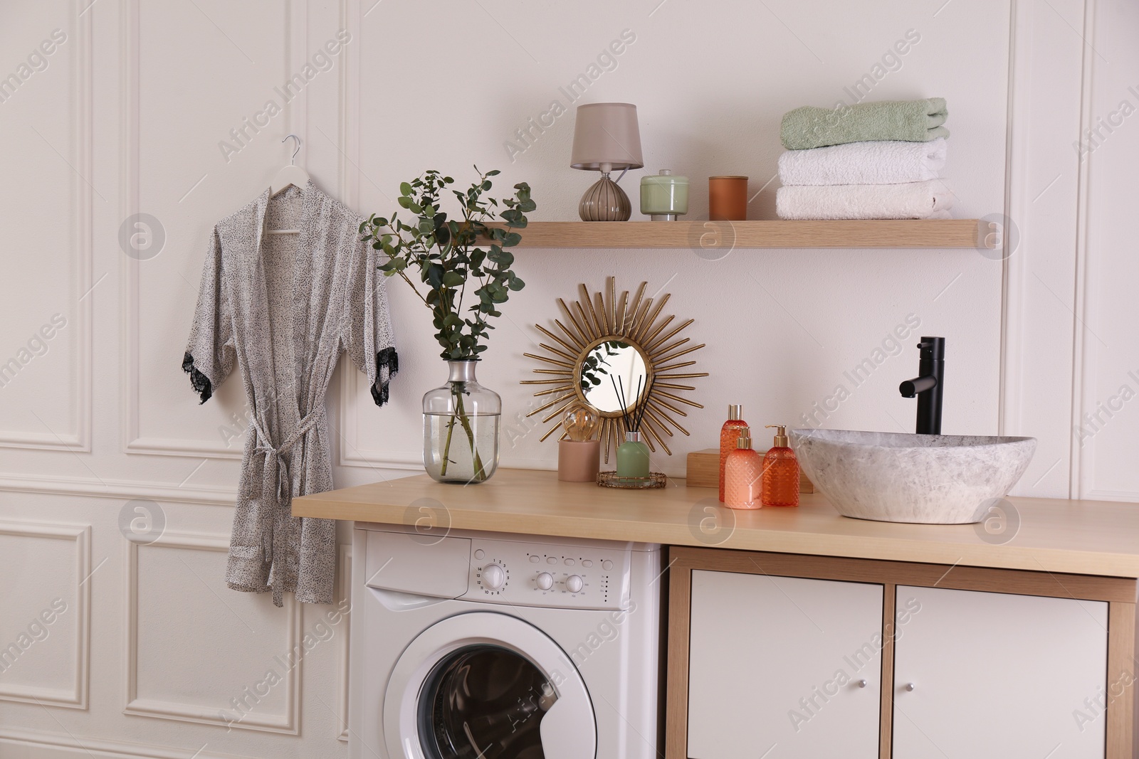 Photo of Laundry room interior with modern washing machine and stylish vessel sink on countertop