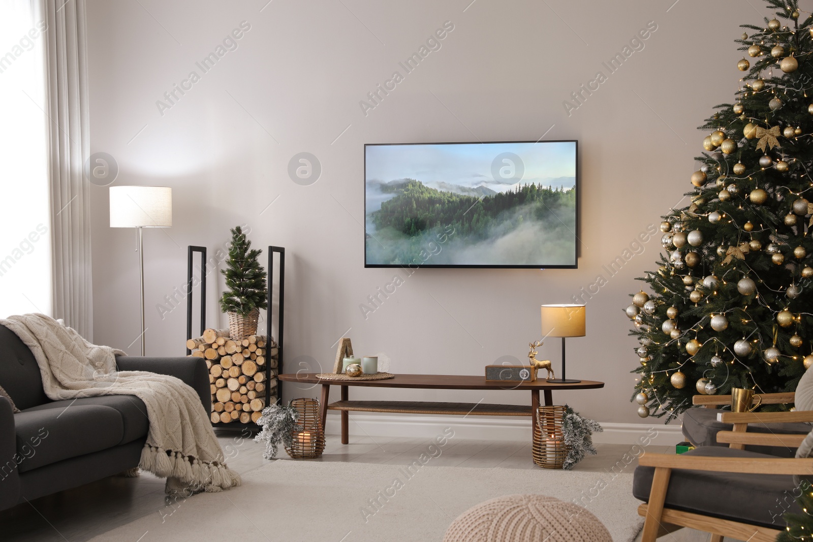 Photo of Modern TV set on light wall in room decorated for Christmas