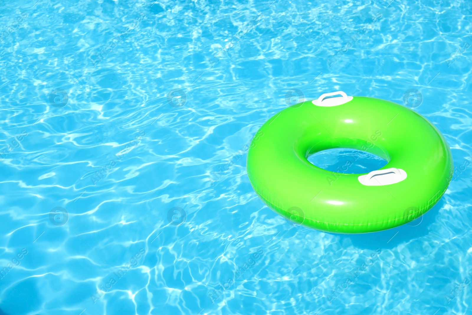 Photo of Inflatable ring floating in swimming pool on sunny day. Space for text