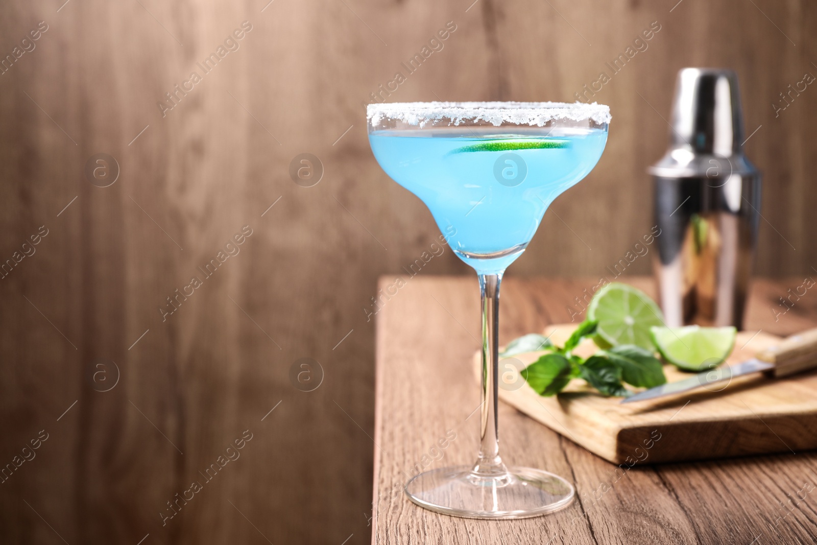 Photo of Bright light blue cocktail on wooden table, space for text