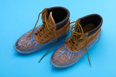 Photo of Men's boots in shoe covers on light blue background, above view