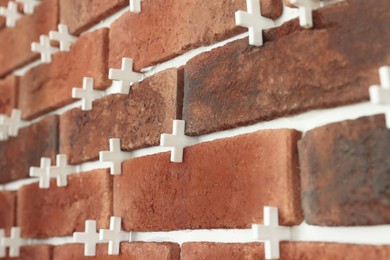 Photo of Decorative bricks with tile leveling system on wall, closeup