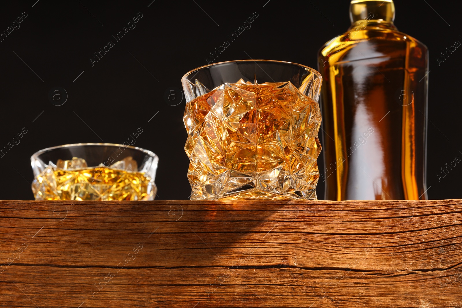 Photo of Whiskey in glasses and bottle on wooden table, low angle view