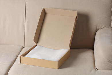 Photo of Open cardboard box on sofa at home