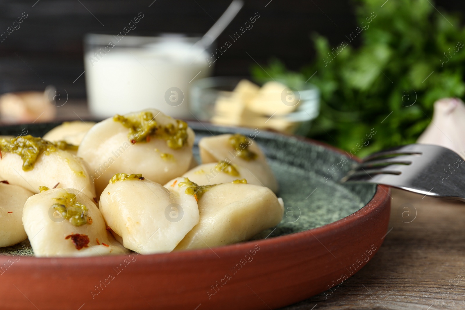 Photo of Delicious cooked dumplings with sauce on wooden table, closeup